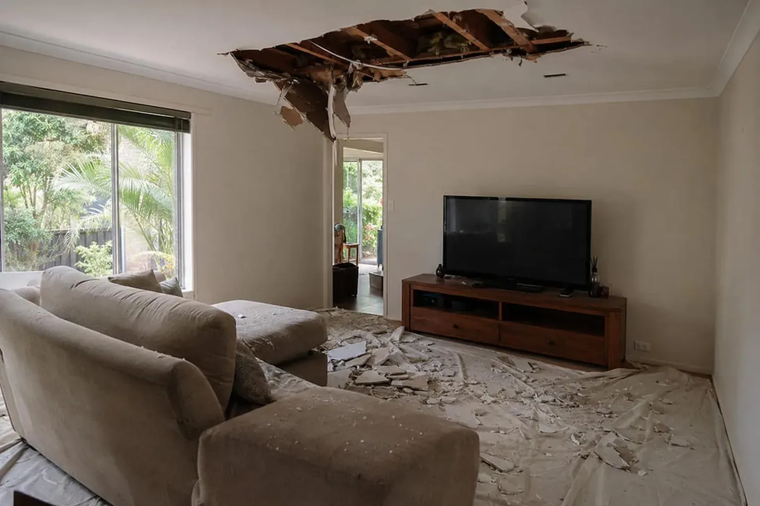 Section of ceiling collapsed onto a lounge suite with broken plaster across the furniture and floor