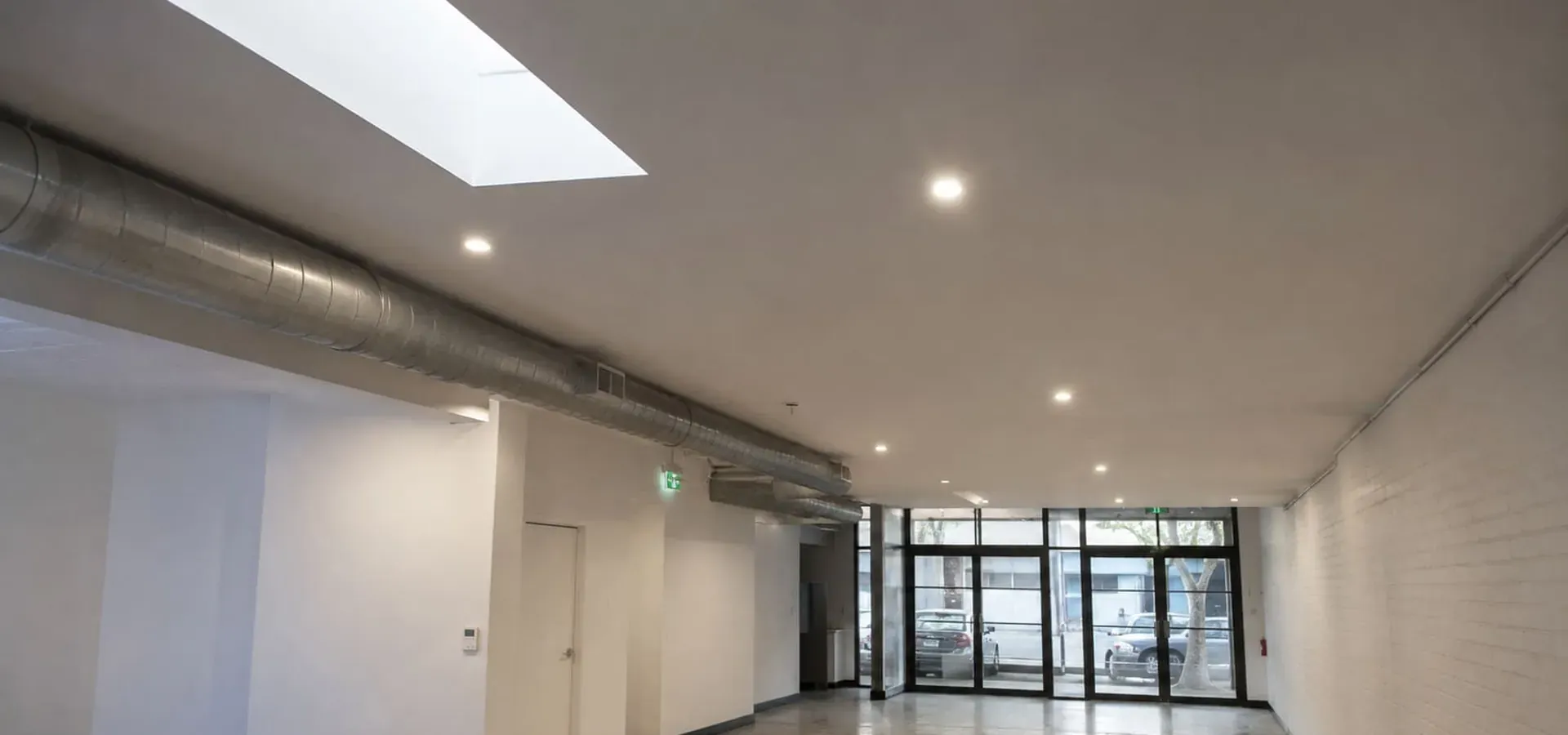 Plasterboard ceiling with exposed ducting and downlights in a converted office