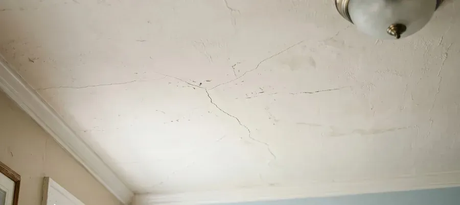 Network of fine cracks spreading across an older plaster ceiling near a light fitting