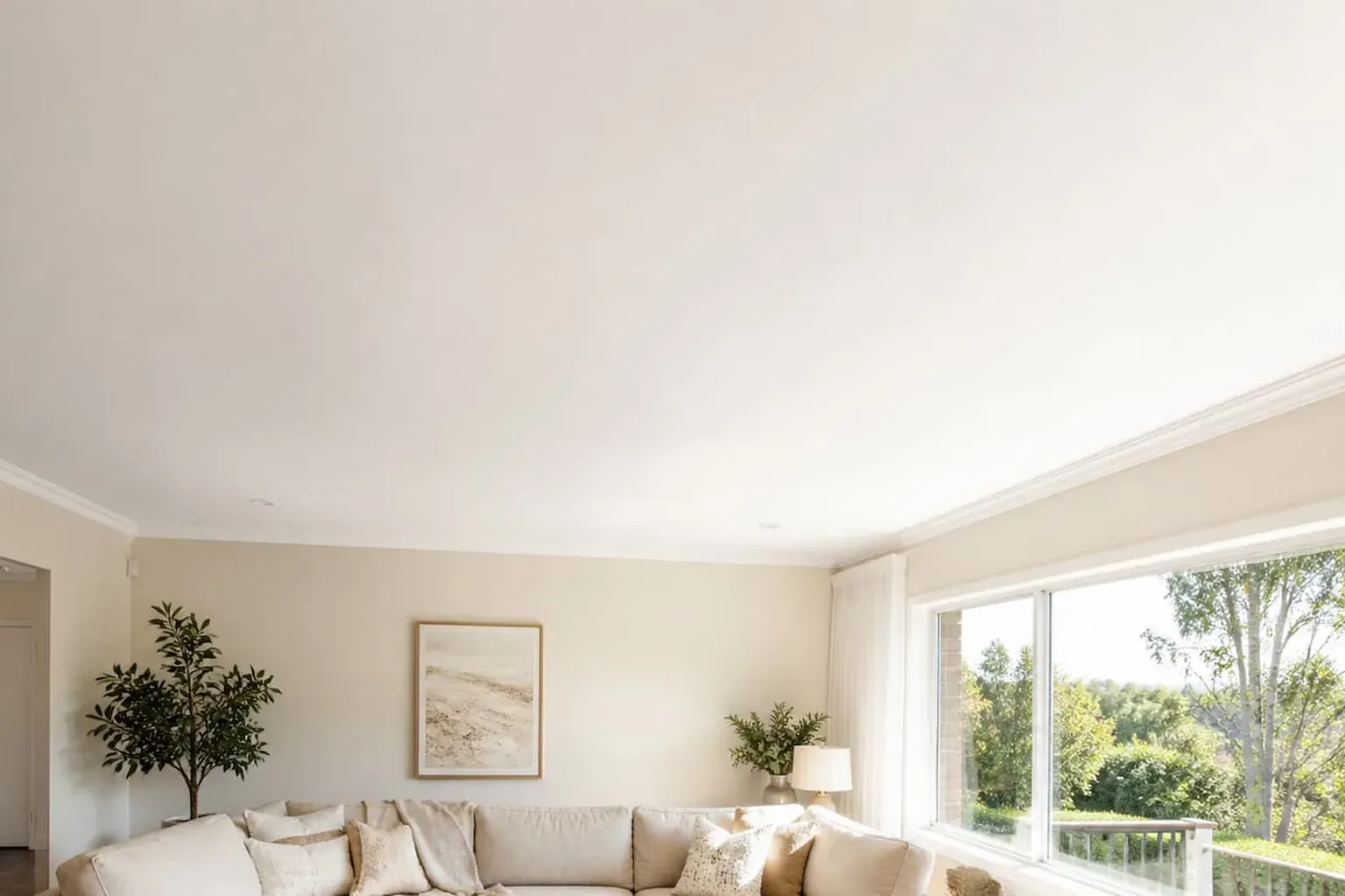 Bright living room with a finished flat ceiling and cornice, lit from a large window