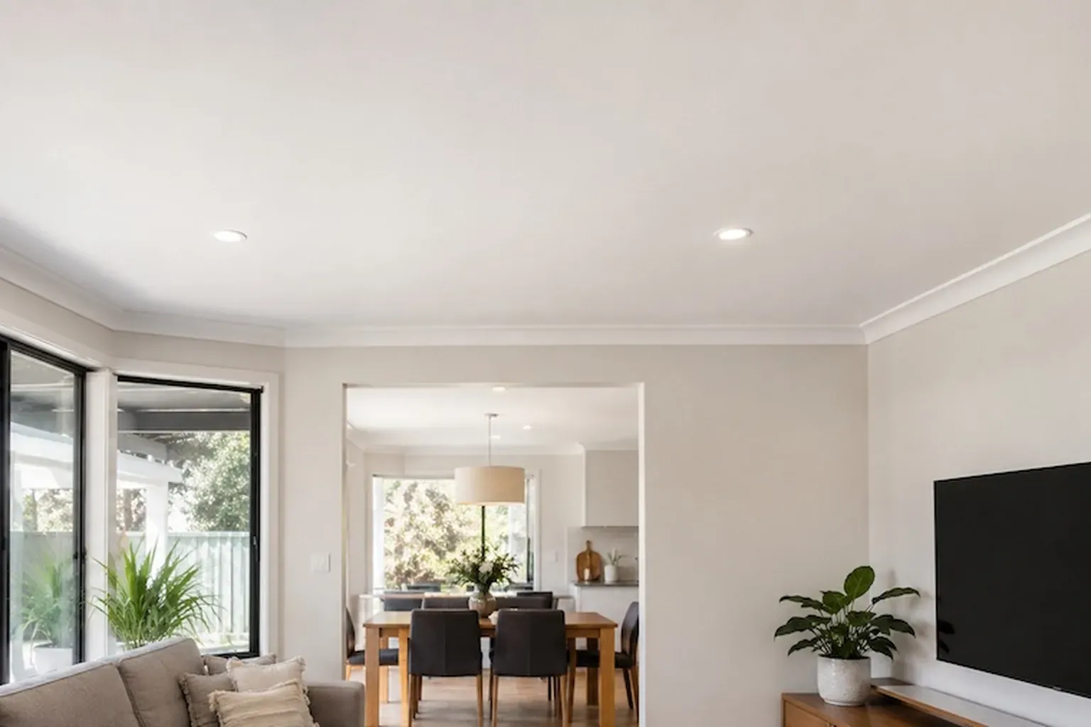 Finished white ceiling with downlights over an open-plan living and dining room