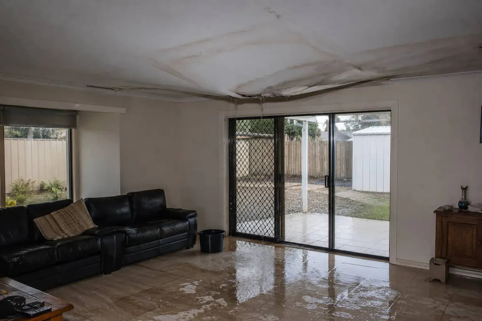 Living room with the ceiling sagging and stained and water pooled across the tiled floor