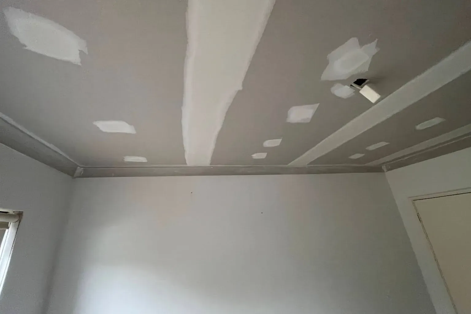 New plasterboard ceiling with the joins taped and every screw head covered with a first coat of setting plaster