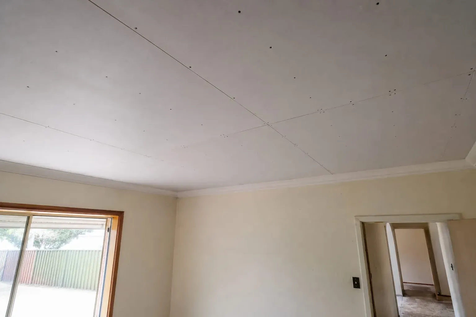 Raked ceiling in an older home covered with new plasterboard sheets, screw heads still visible