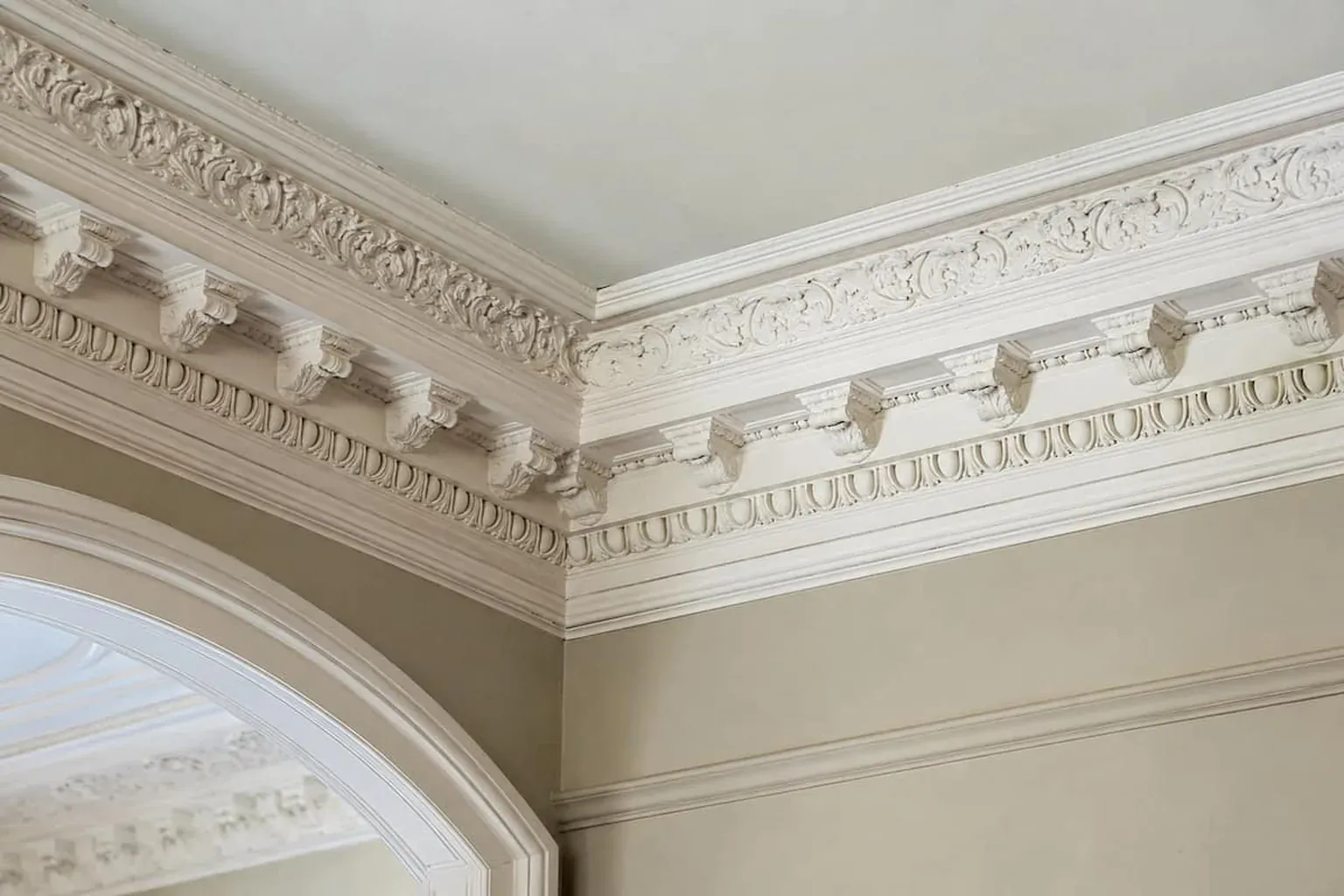 Ornate plaster cornice with dentils and acanthus-leaf moulding above an arched window in a heritage home