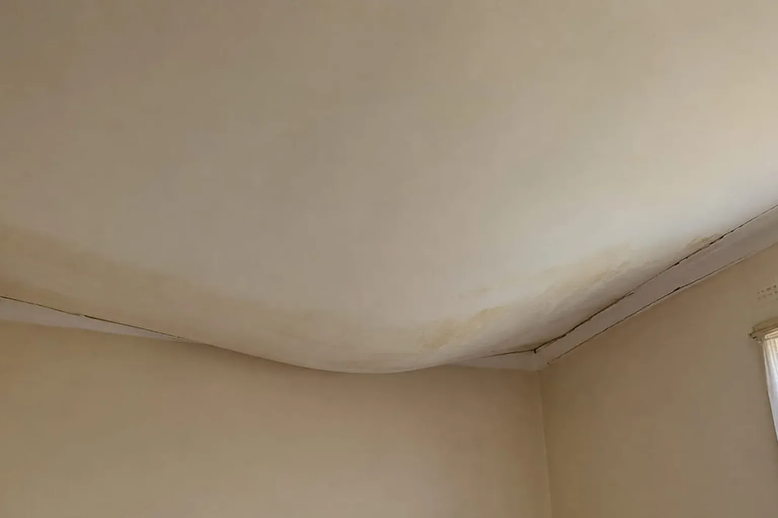 Plasterglass ceiling sagging and pulling away from the cornice along one wall, with a crack opening at the join