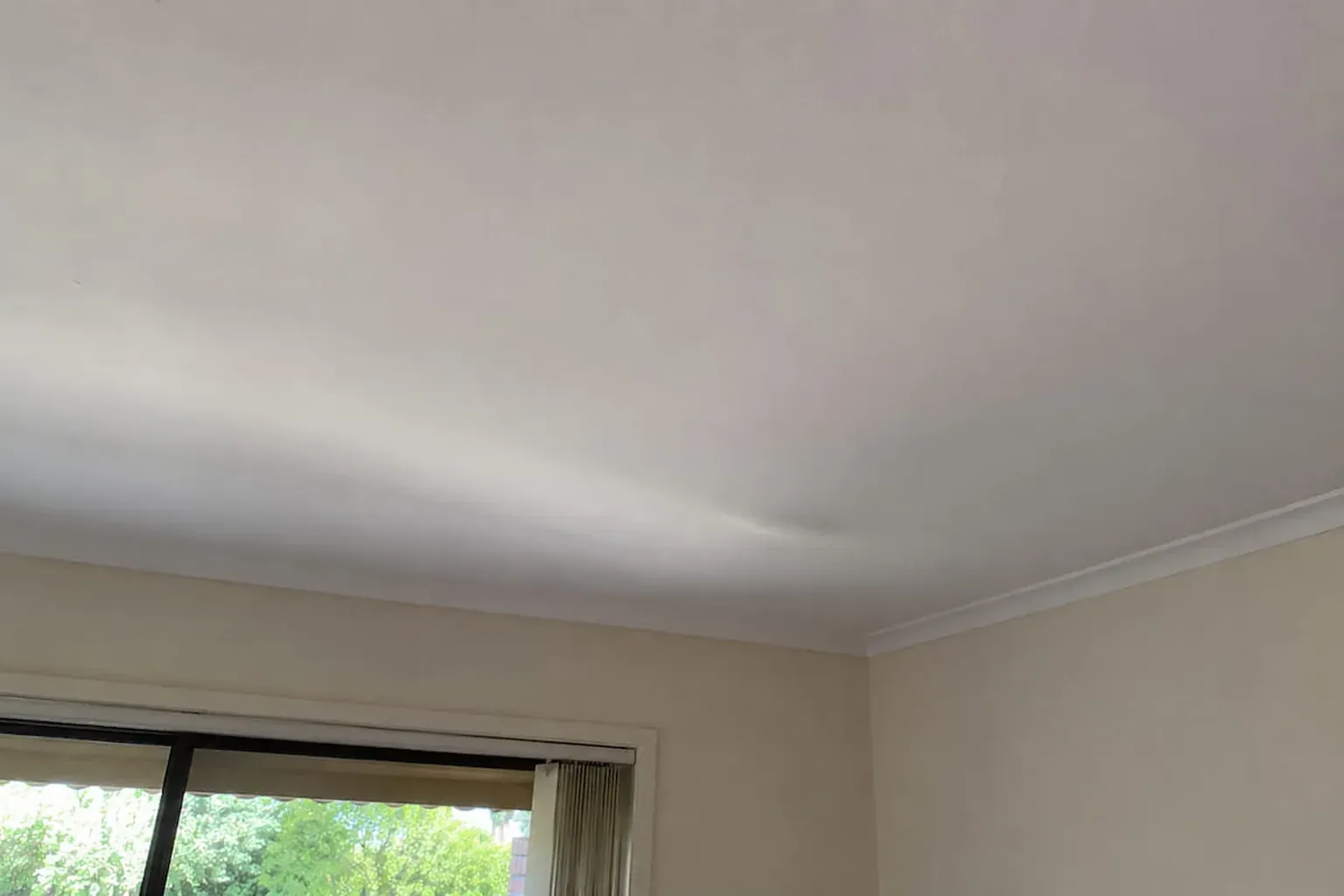 Bedroom plasterglass ceiling with a shallow sag spreading from the window wall toward the cornice