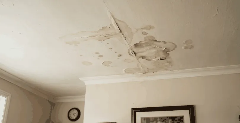 Water stains and cracking in the corner of a ceiling where it meets the cornice